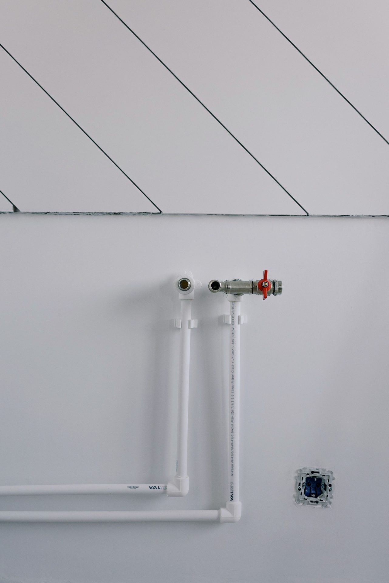 Clean white plumbing pipework on a wall