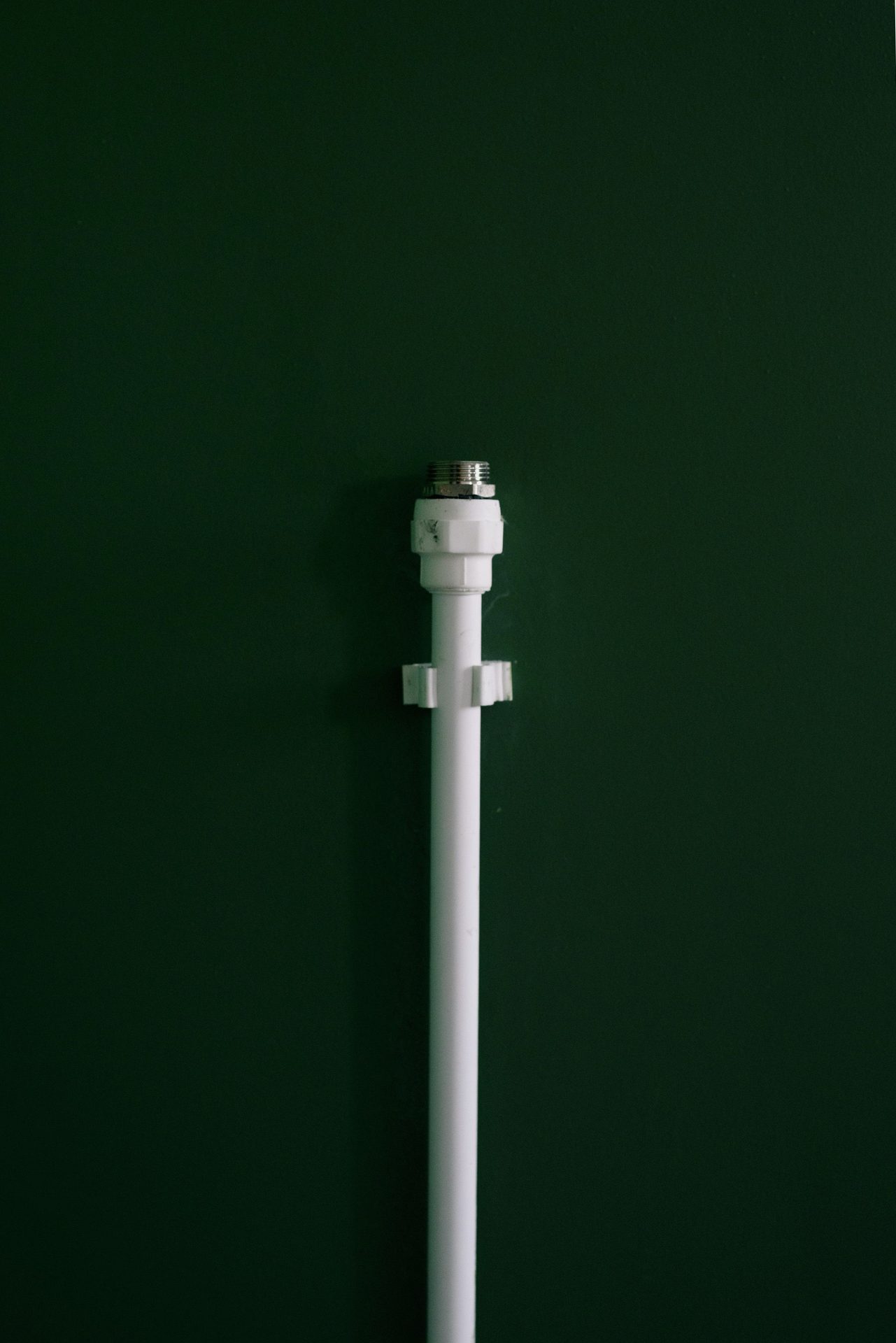 Single white water pipe against a dark wall