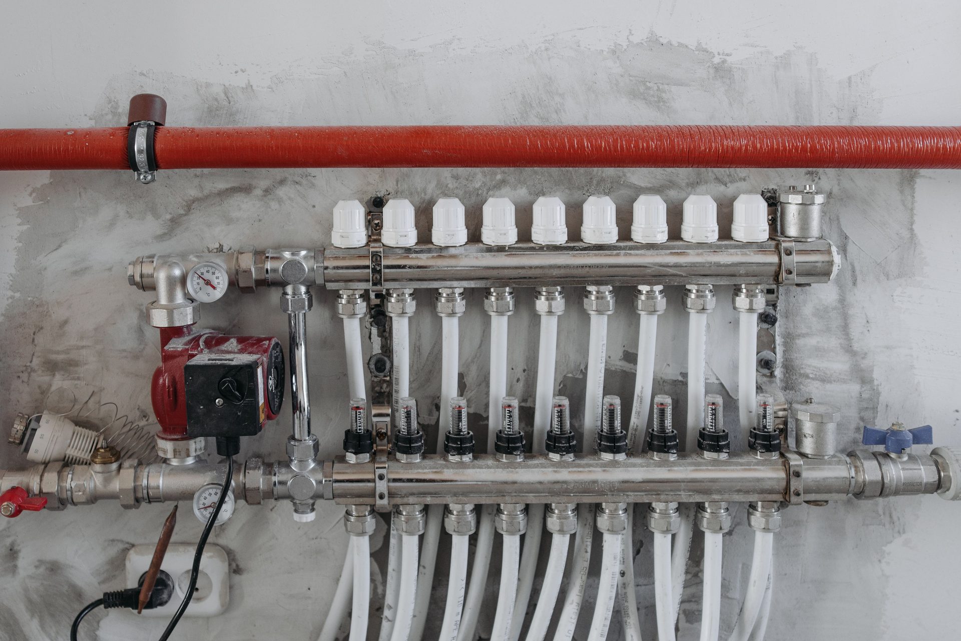 Steel underfloor heating manifold with a red circulation pump
